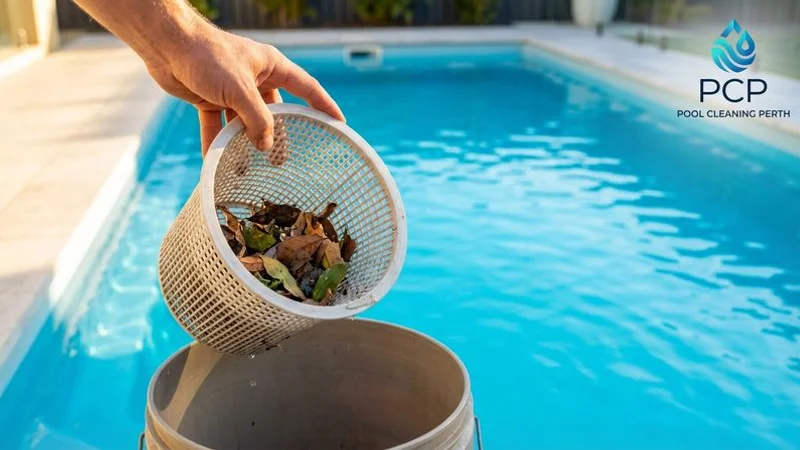 Close up of a pool skimmer basket being emptied with clear blue pool water visible in the background